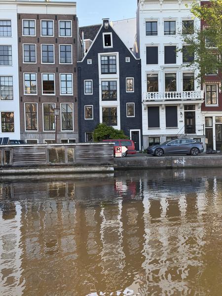 This photo captures a tranquil view of the Amstel canal in Centrum, Amsterdam, showcasing classic canal houses with their distinct architecture